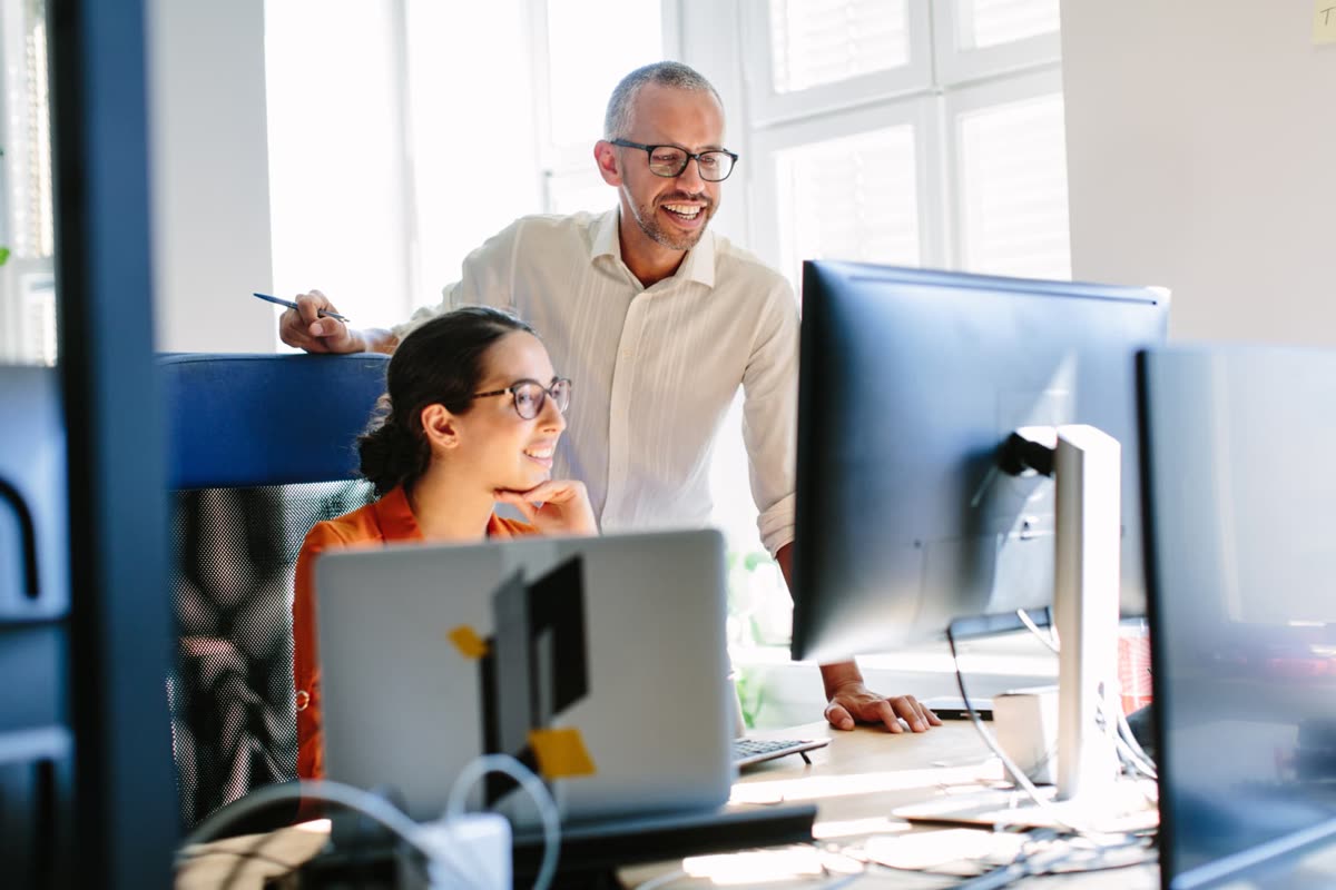 Two colleagues reviewing deal registration data together on a monitor